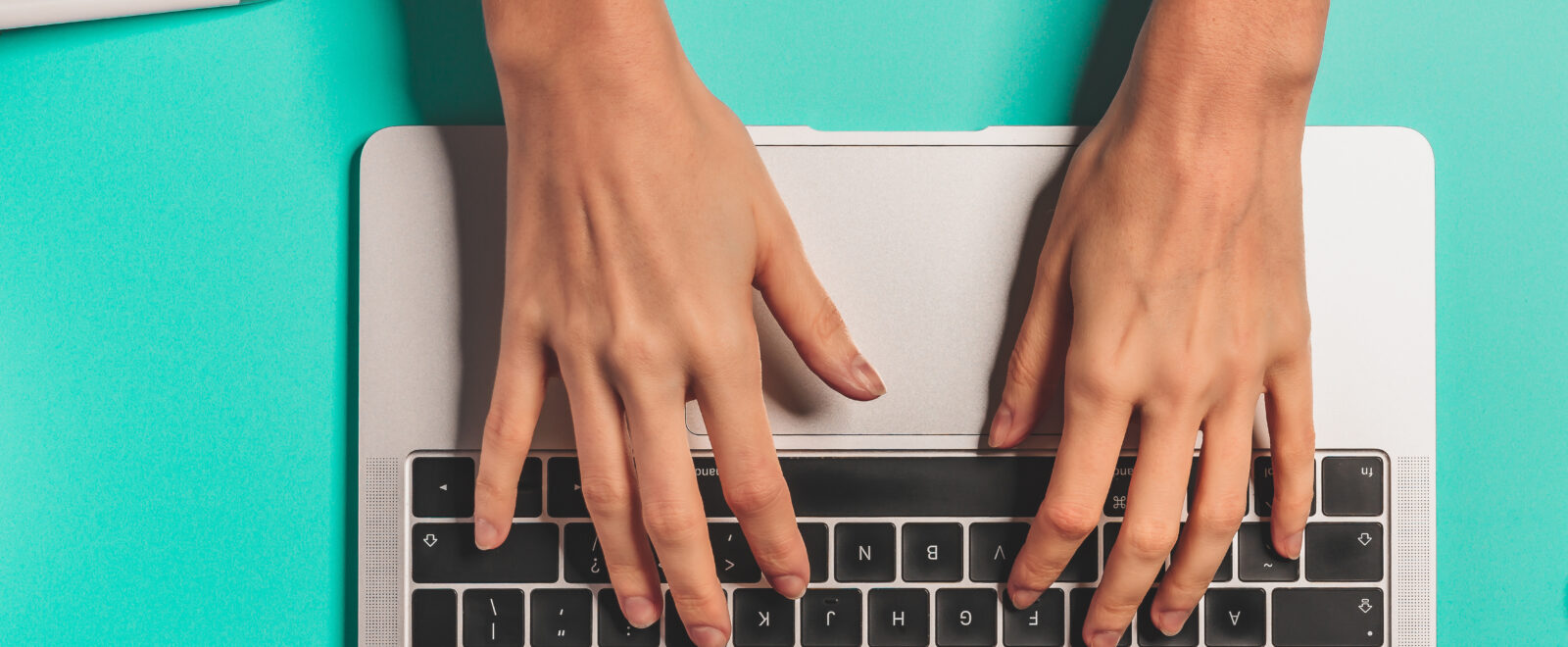 Overhead view of the working woman hands typing on keyboard notebook laptop computer at office desk