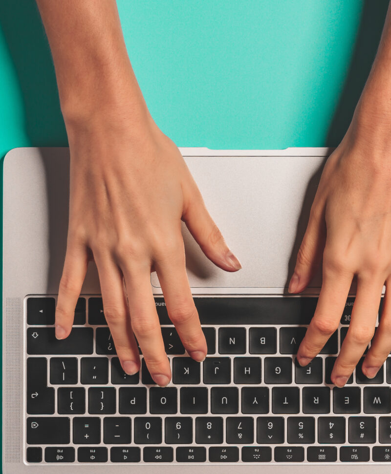 Overhead view of the working woman hands typing on keyboard notebook laptop computer at office desk