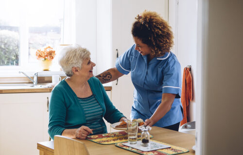 Carer serving meal to a lady