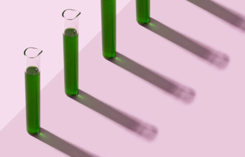Row of test tubes with liquid, pink background