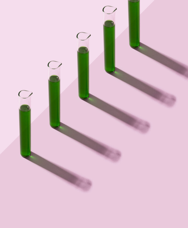 Row of test tubes with liquid, pink background